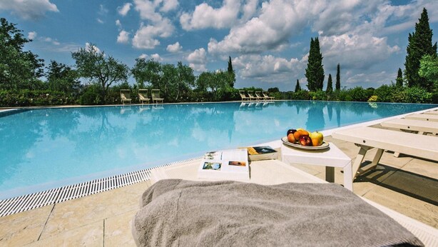 A swimming pool with lounge chairs, a towel, and a plate of fruit. - Apartment in Santo Pietro Belvedere With Pool-formerly TUI Ferienhaus (Capannoli)