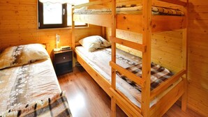 A wooden cabin room with bunk beds, a nightstand with a lamp, and a window with curtains. - Cottages in a Quiet Neighborhood, Rusinowo (Postomino)