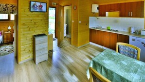 A cozy wooden cabin with a kitchen, dining area, and a small bedroom. - Cottages in a Quiet Neighborhood, Rusinowo (Postomino)