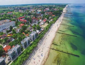 Vista aérea de un pueblo costero con playa, edificios y una visión despejada del mar.