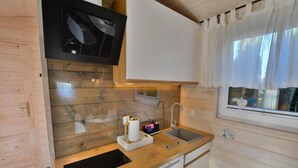 Eine kleine Küche mit Holzwänden, einer eingebauten Mikrowelle, einem Spülbecken und einem Geschirrspüler.