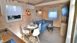 Ein gemütliches Blockhaus-Interieur mit Essbereich, einer Couch und einem Fernseher.