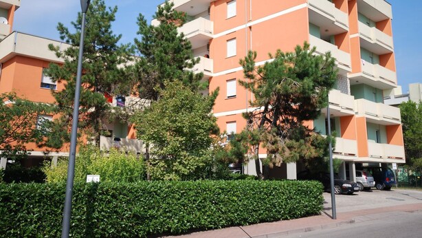 A multi-story residential building with balconies, surrounded by greenery and a street lamp. - Apartments Cormoran, Bibione Lido del Sole (San Michele al Tagliamento)