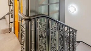 A modern staircase with ornate metal railings and a glass door.