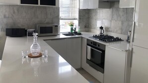 A modern kitchen with a central island, built-in microwave, stove, and oven.