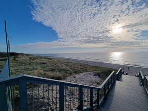 A wooden boardwalk leading to a beach with dunes and a clear sky. - Unique Apartment With a Balcony in Darlowko (Darlowo)