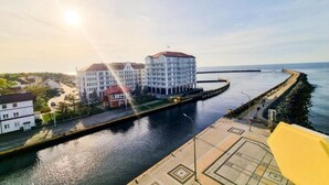 A waterfront hotel with a large building, a dock, and a calm river. - Unique Apartment With a Balcony in Darlowko (Darlowo)