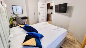 A hotel room with a bed, a desk, a chair, a TV, and a wardrobe. - Unique Apartment With a Balcony in Darlowko (Darlowo)