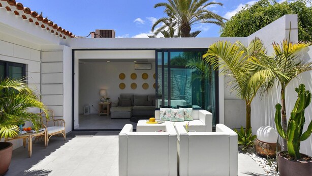 An outdoor living area with white sofas, a dining table, and potted plants. - Bungalow, Playa del Ingles (San Bartolomé de Tirajana)