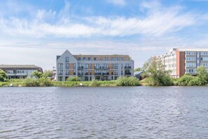 A modern building with a flat roof and multiple windows, situated next to a body of water. - Appartement in Fantastischer Lage auf Nordstrand (Nordstrand)