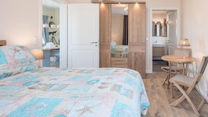 A bedroom with a bed, a desk, a chair, and a small table with a lamp. - Appartement in Fantastischer Lage auf Nordstrand (Nordstrand)