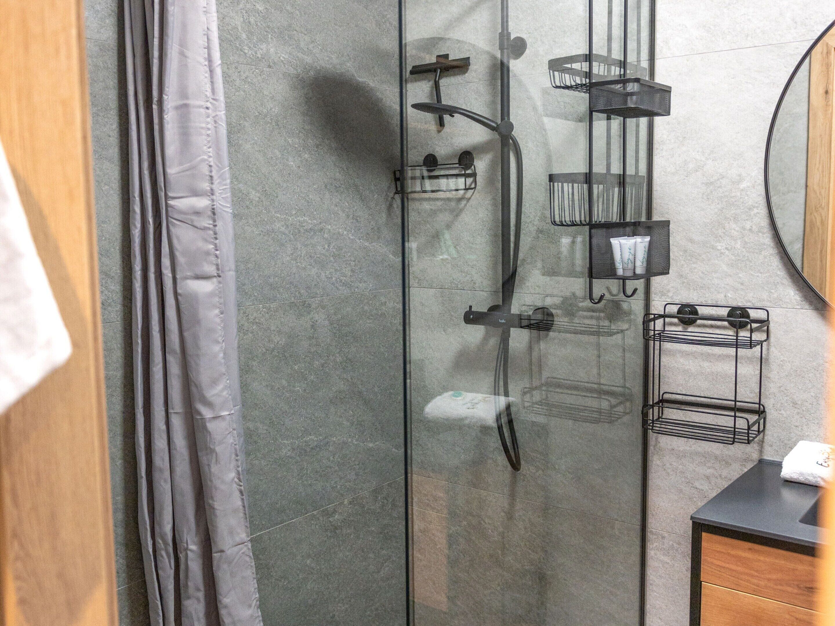 Un baño moderno con cabina de ducha de vidrio, tocador de madera y toalleros empotrados.