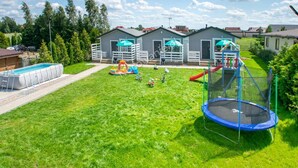 A backyard with a swimming pool, a trampoline, and a play area with inflatable toys. - 2-person Studio in the Attic, Sarbinowo (Mielno)