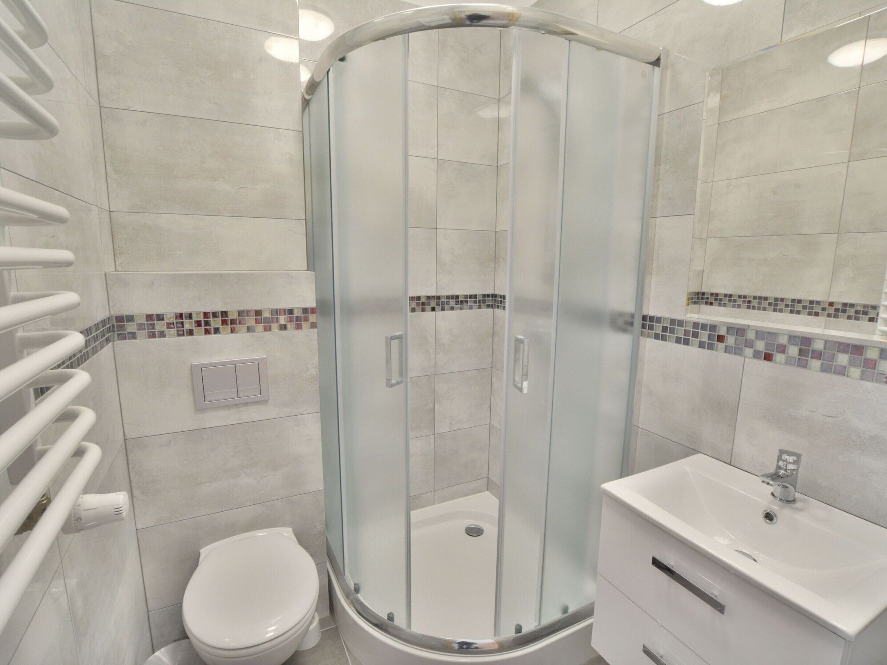 A modern bathroom with a glass-enclosed shower, a white toilet, and a vanity with a sink.