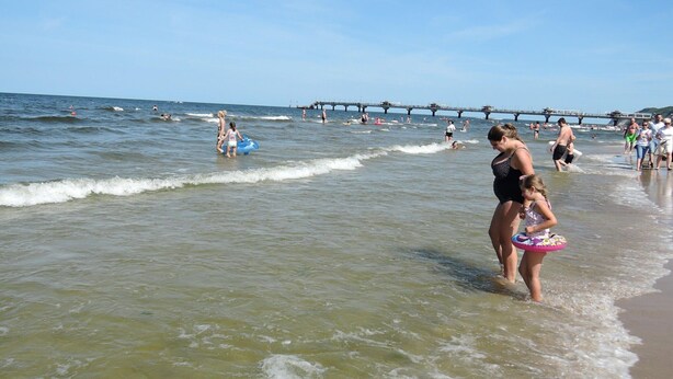 A beach scene with people swimming and walking along the shore. - Holiday Home in Kolczewo for Nature Lovers (gmina Wolin)