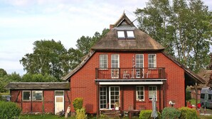 A red brick house with a balcony, a small attached shed, and a well-maintained garden. - Apartment Wiesenschein, Moenkebude (Monkebude)