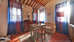 Une pièce avec un plafond en bois, une table entourée de chaises, un canapé, une commode et un tapis.