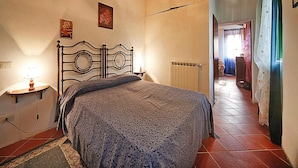 Une chambre à coucher avec un lit, un radiateur, une lampe et un luminaire au plafond.