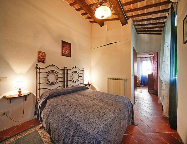 Una camera da letto con un letto, un termosifone, una lampada e una luce a soffitto.