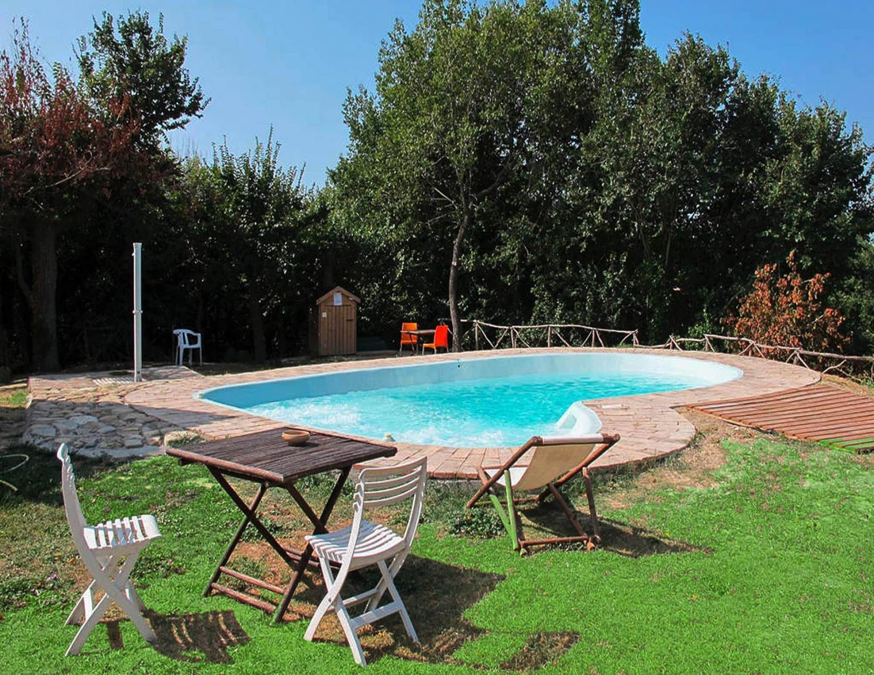 A backyard with a swimming pool, a wooden deck, and outdoor furniture including a table and chairs.