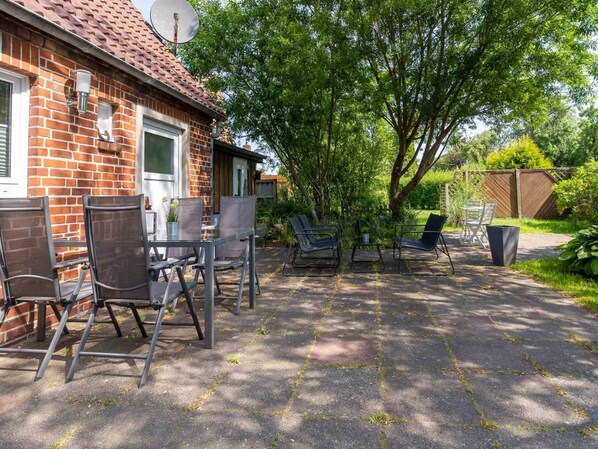 A brick house with a patio area featuring outdoor furniture and a satellite dish. - Ferienhaus in Tonning (Toenning)