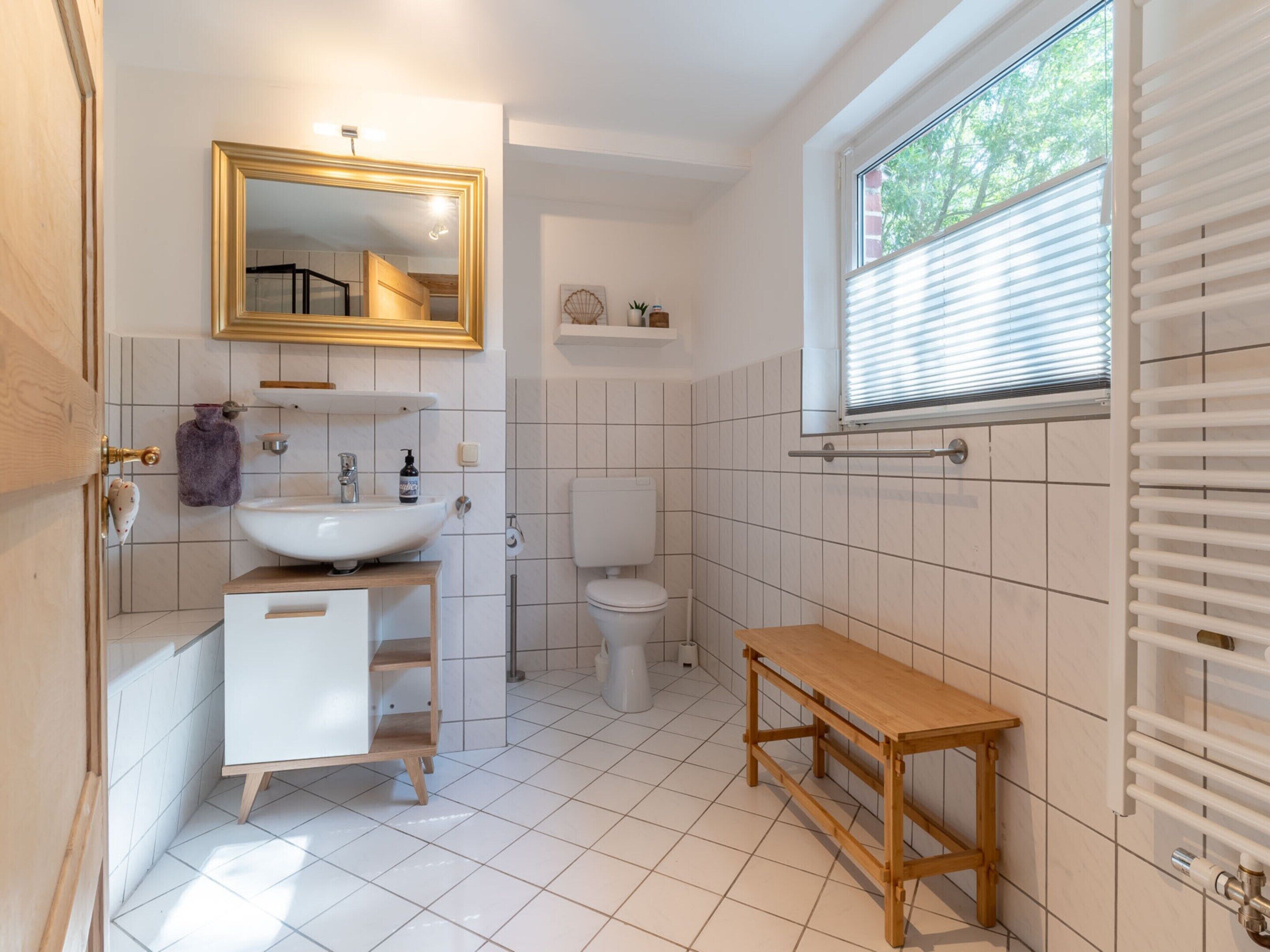 A bathroom with a white sink, toilet, and wooden bench.