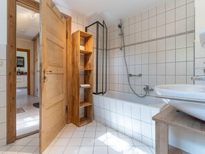 A bathroom with a wooden door, a shower, a bathtub, and a sink.