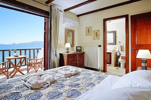 Ein Schlafzimmer mit Bett, Schreibtisch, Stuhl und Meerblick, sowie ein Badezimmer.