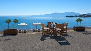 A seaside terrace with tables, chairs, and umbrellas overlooking calm waters. - Detached Villa With Seaview in Charaki (Rhodes)