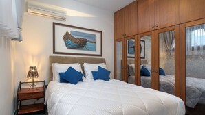 A bedroom with a large bed, a nightstand, a framed picture, and a wardrobe with mirrors. - Detached Villa With Seaview in Charaki (Rhodes)
