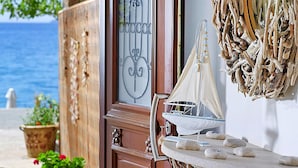 A wooden door with a glass panel, a small sailboat model on a table, and a decorative wall hanging. - Detached Villa With Seaview in Charaki (Rhodes)