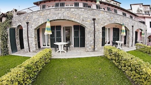 A stone building with a curved balcony, outdoor seating, and well-maintained hedges. - Apartment in Castellaro With Balcony (Casanova Lerrone)