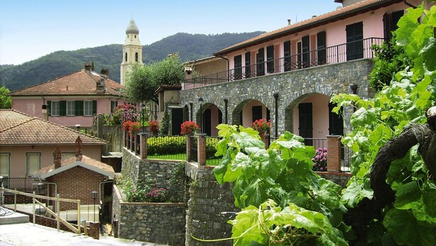 A historic building with a stone facade, arched windows, and a balcony overlooking a garden with flowering plants. - Apartment in Castellaro With Balcony (Casanova Lerrone)