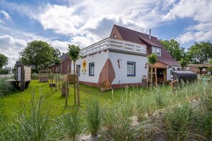 Ein zweistöckiges Haus mit weißer Fassade und roten Backsteinakzenten, einem umzäunten Garten und einer kleinen Pflanzenauslage mit Blumentöpfen.