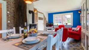 A dining area with a brick wall, a wooden table set for two, and a red chair. - Holiday Home in Tating (Tating)