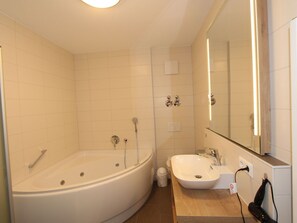 Et moderne badeværelse med et stort badekar, en vask og et spejl.