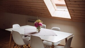 A dining area with a table, chairs, and a vase of flowers.