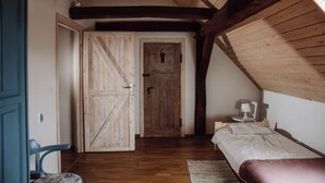 A bedroom with a wooden ceiling, a bed, a nightstand, and a chair.