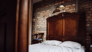 A bedroom with a wooden bed, a brick wall, and a wooden wardrobe. - Apartment in Gronowo Near Lake Siecino (Zlocieniec)