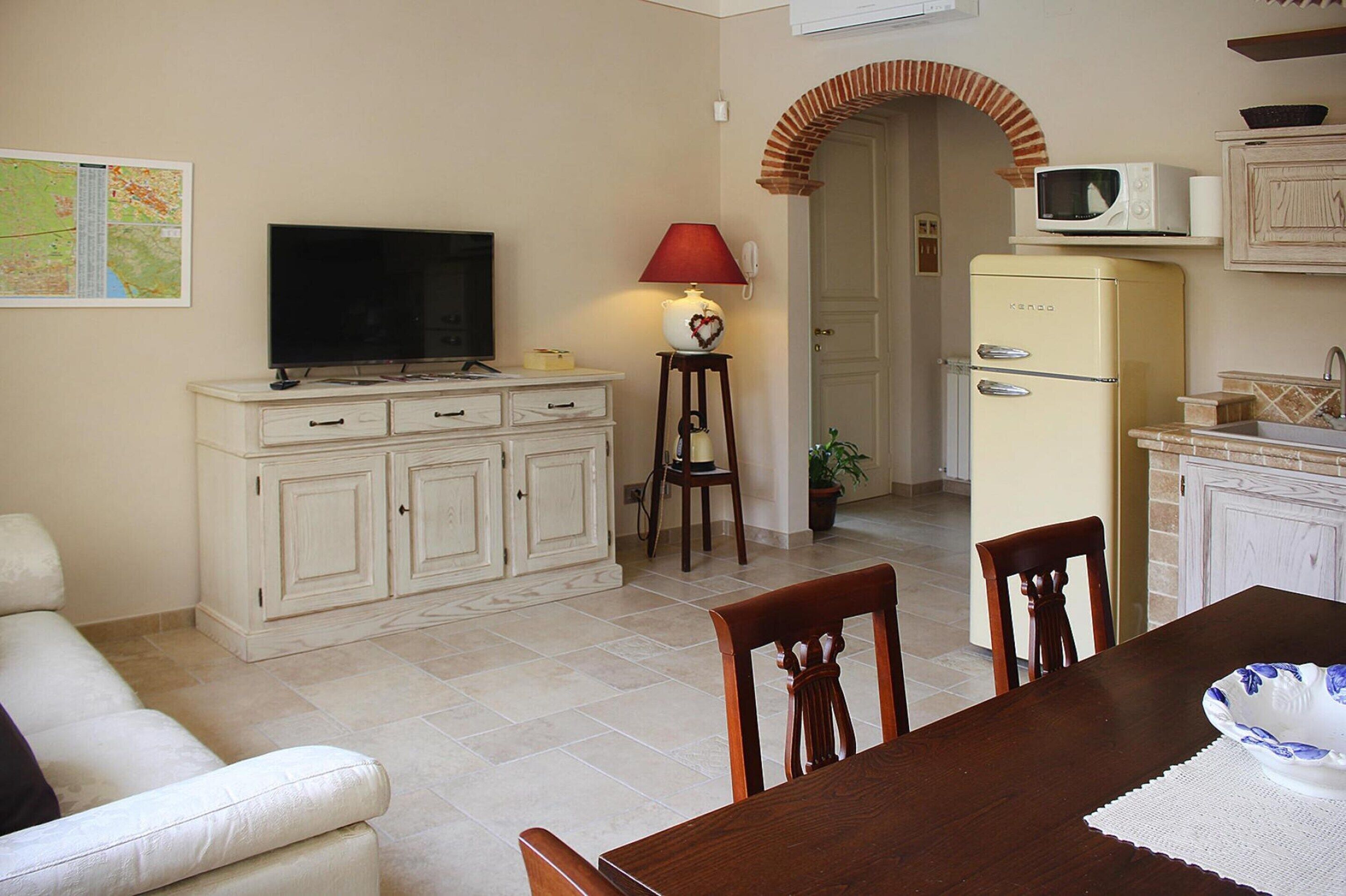A compact living space with a television, a dining table, and a kitchenette area.
