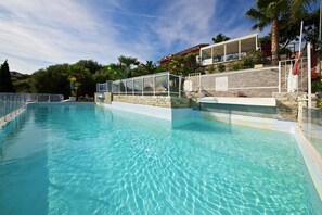 A clear swimming pool with a stone wall and a covered area with a roof. - Holiday Villa Apartment in Imperia (Imperia)