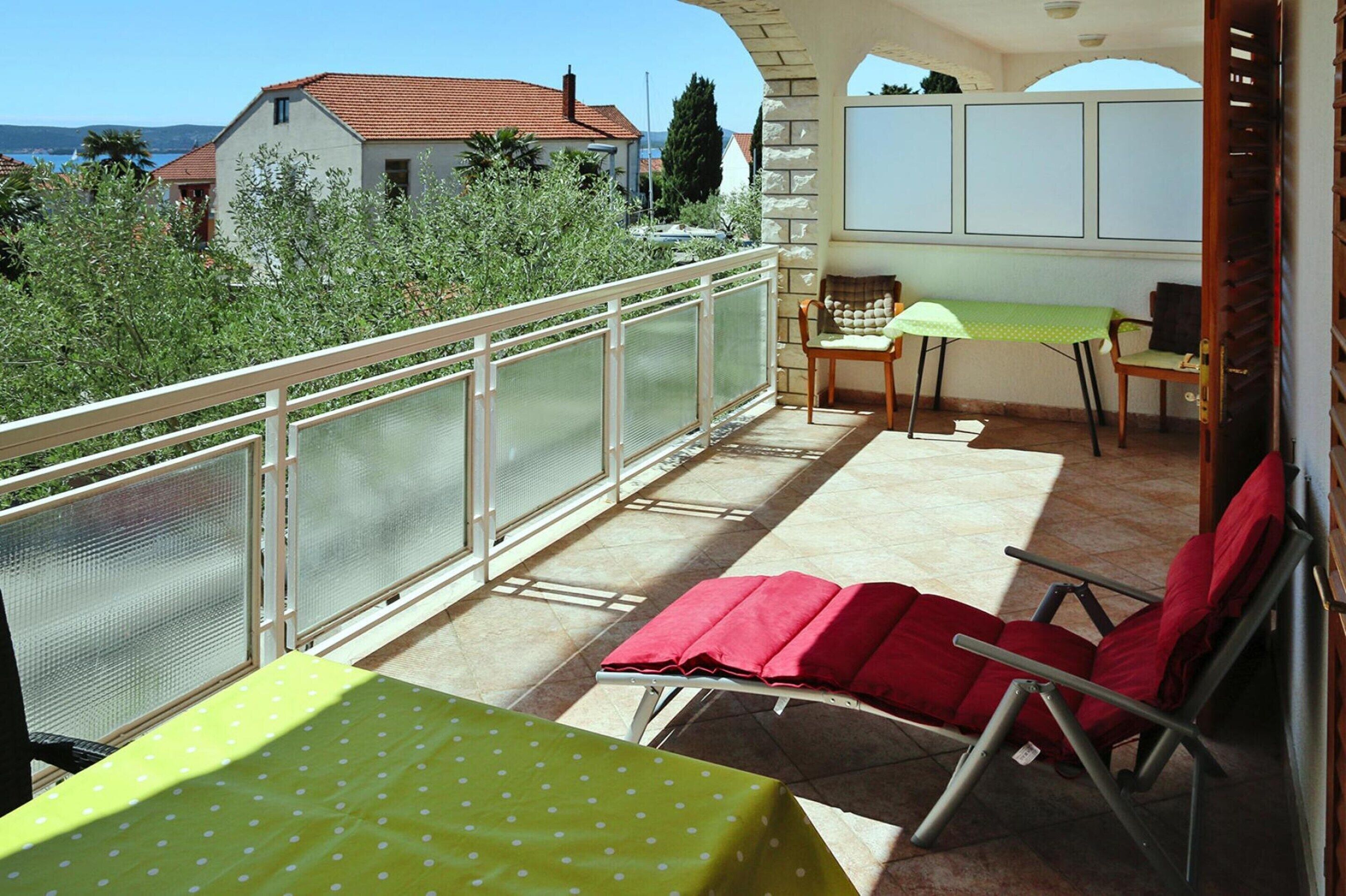 A balcony with a table and chairs, a view of houses, and a clear sky.