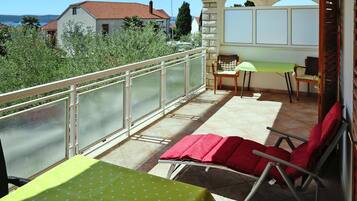 A balcony with a table and chairs, a view of houses, and a clear sky.