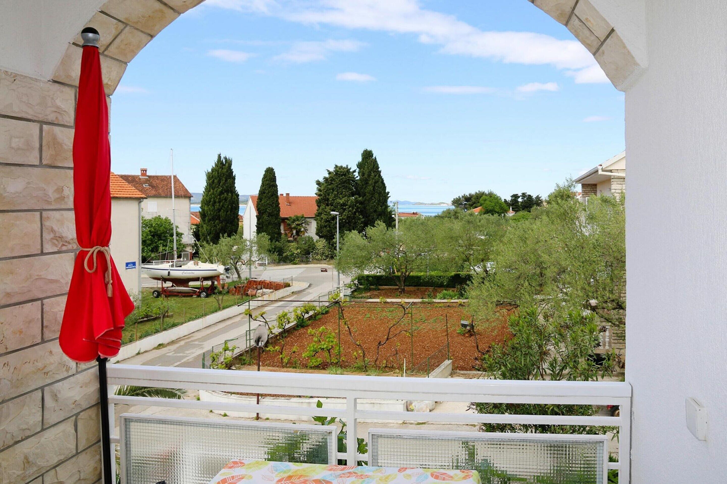 A balcony with a view of a road, trees, and a distant body of water.
