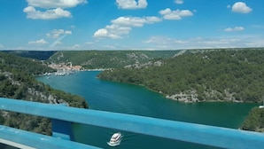 Une vue pittoresque d’une rivière avec un bateau, entourée d’une végétation luxuriante et de collines.