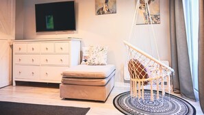 Een gezellige slaapkamer met een bed, een hangstoel, een dressoir en kunst aan de muren.