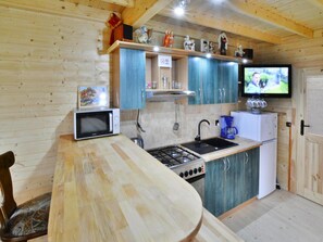 A compact kitchen with a microwave, stove, sink, and a refrigerator. - Wooden House by Ostrowieckie Lake With Beach (Malechowo)