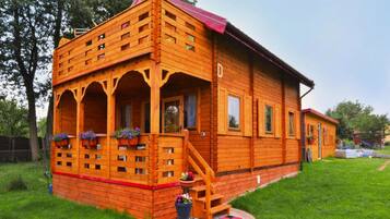 A wooden cabin with a porch, a staircase, and a small garden area.