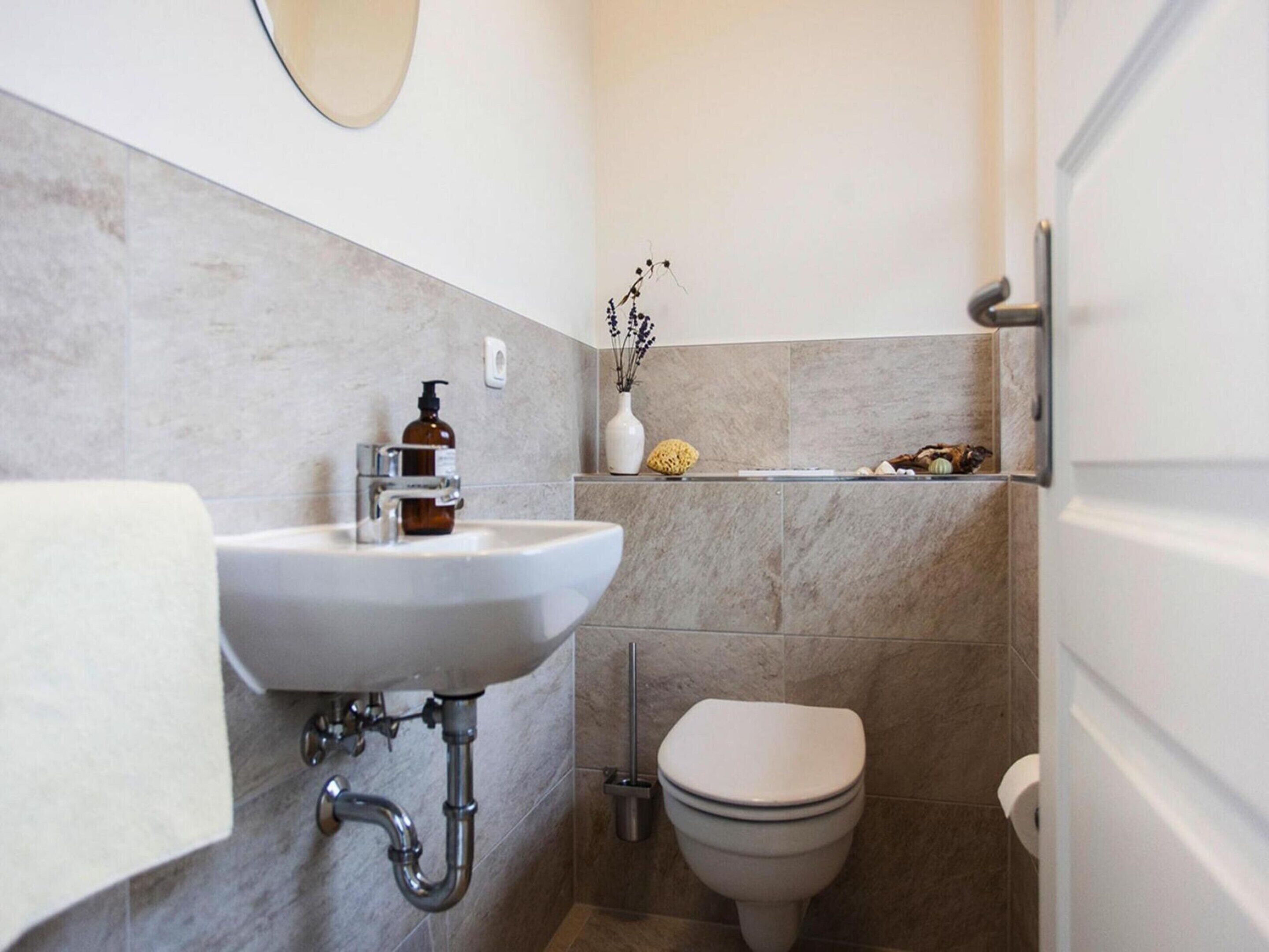 A bathroom with a sink, toilet, and a shelf with decorative items.