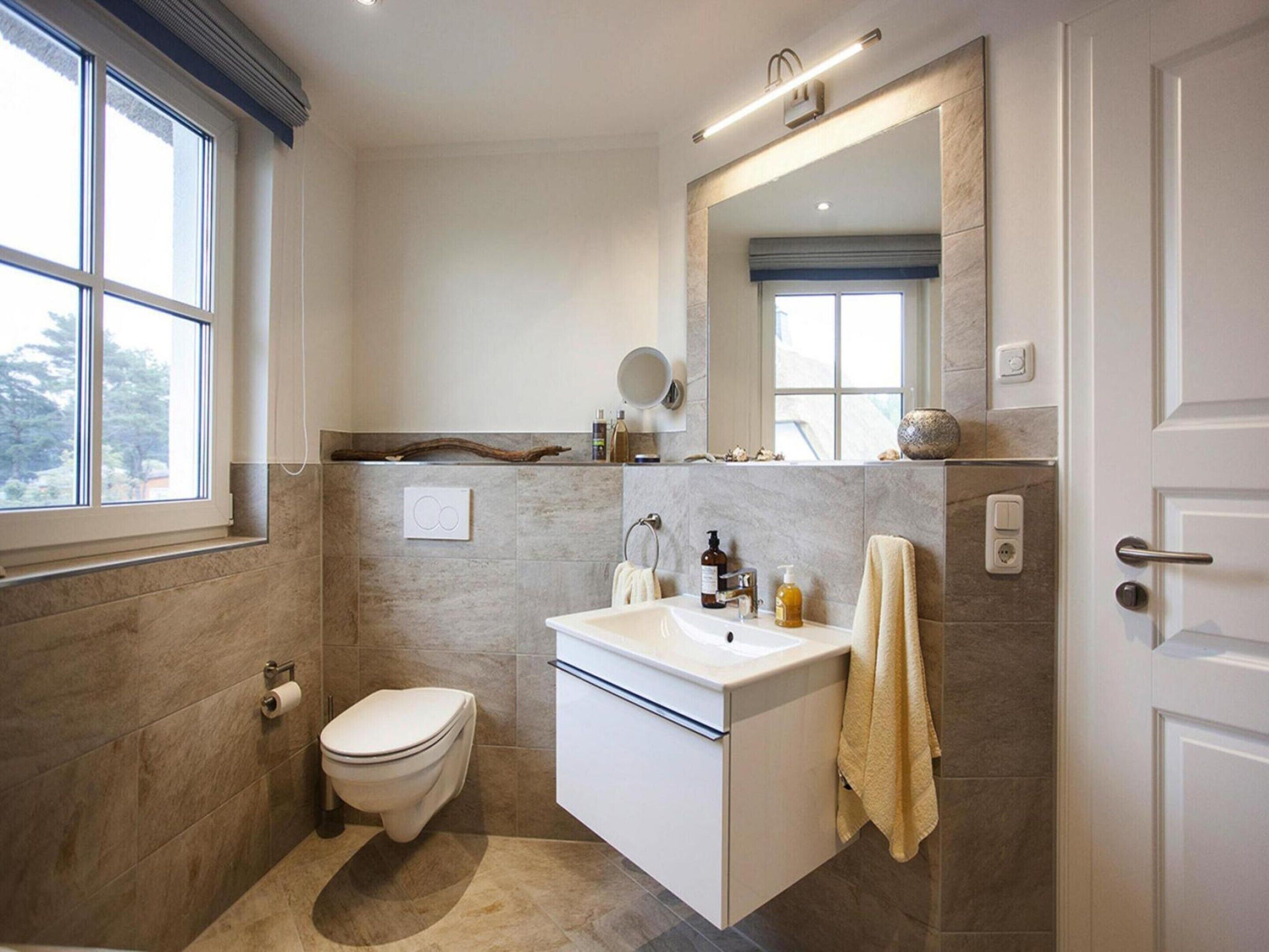 A modern bathroom with a toilet, sink, and mirror.